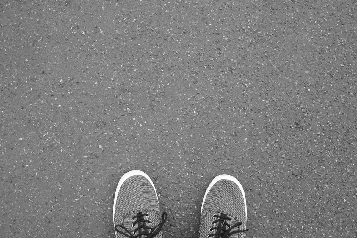 Feet in Canvas Shoes Standing on the Street