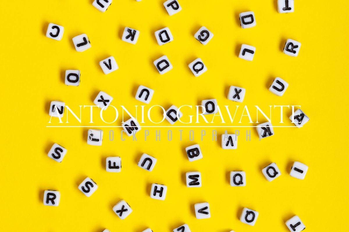 White Cubes with Letters Scattered Randomly on a Yellow Background.