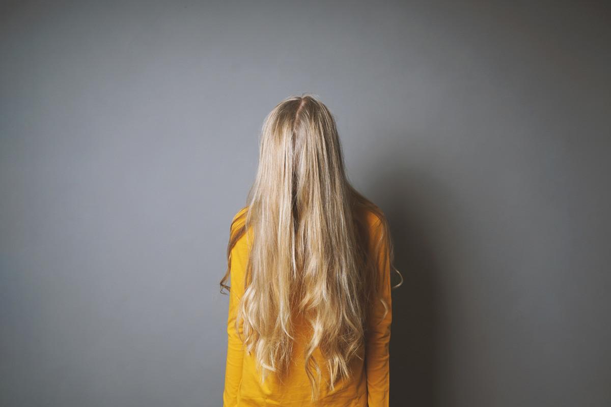 Depressed Young Woman Hiding Her Face Behind Long Blond Hair