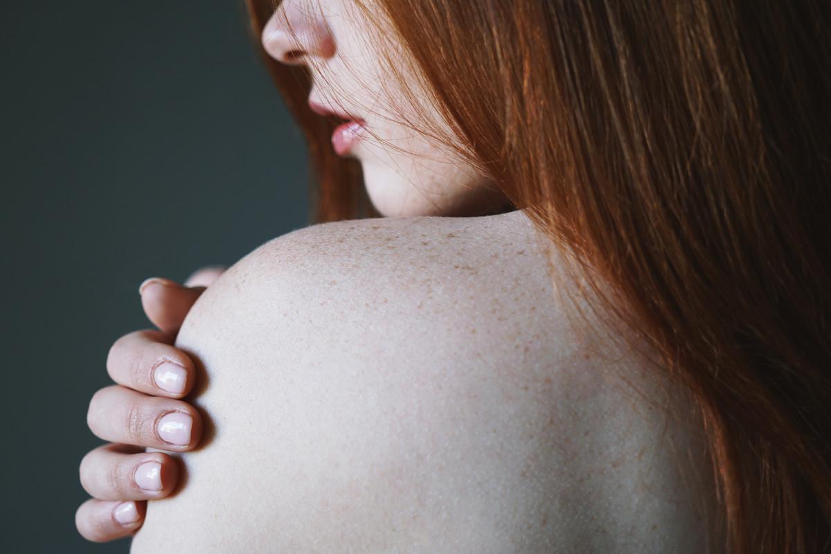 Young Woman with Red Hair and Freckles on Bare Shoulder