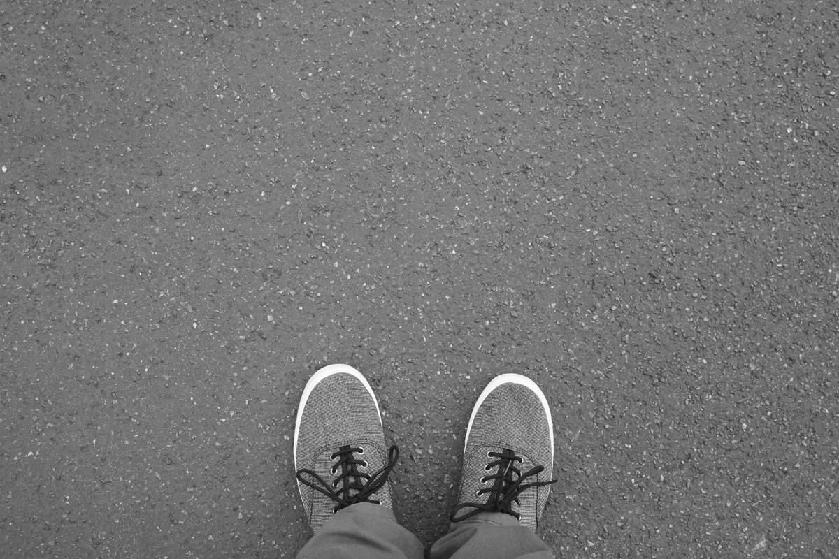 Feet in Canvas Shoes Standing on Asphalt Street